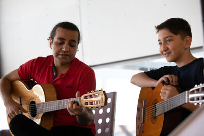 Adult and young person playing guitars
