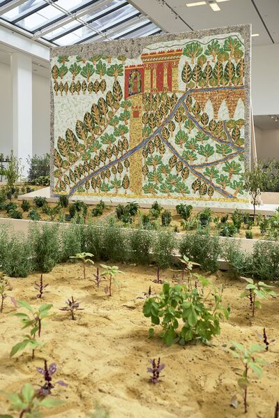A large panel in the gallery collaged into a garden image is surrounded by plants growing in sand