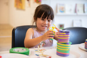 Girl making colourful shapes out if paper and tape.