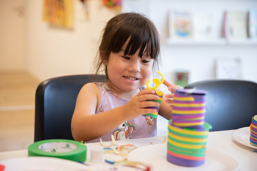 Girl making colourful shapes out if paper and tape.