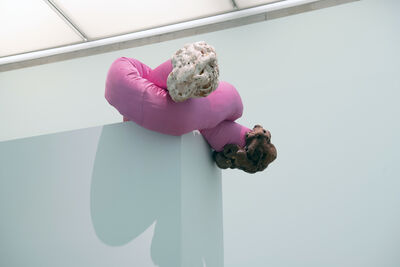 A sculpture of a pink fabric tube tied in a knot with expanding foam leaking out the ends.