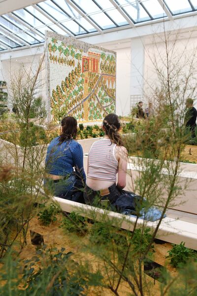 Two people sat in exhibition among the plants.