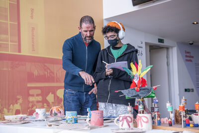 Two people stand looking at their crafts