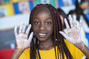 Young girl with white paint on her hands staring into the camera
