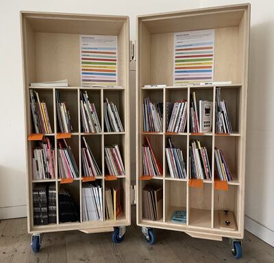 Fold out wooden shelves with zines stacked in them.