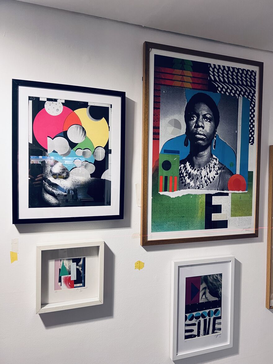 White wall with four framed artworks displayed in bright colours.