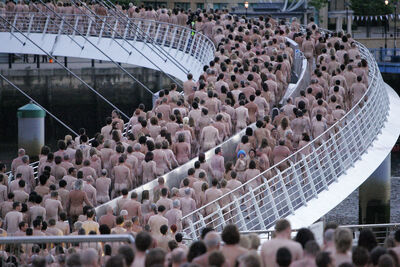 Lots of naked people walking up a bridge