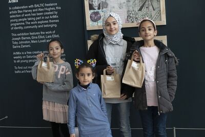 Four young people smiling and holding up food bags