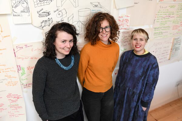 Three people stood in front of wall covered in notes and illustrations