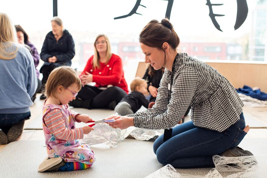 Adult assisting child to cut paper