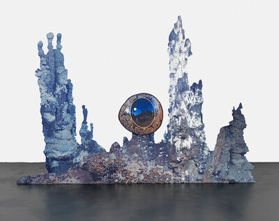 A blue sculpture of coral with an eye at the centre of it.
