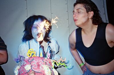 Two people blow out birthday candles.