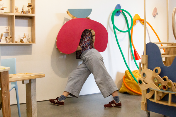 Person hiding behind 3D abstract shape with legs sticking out.