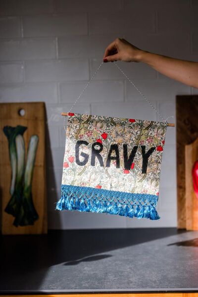 A patterned wall hanging that reads 'gravy'