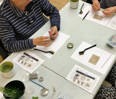 Three people are focused on their silver clay creating at the workshop table.