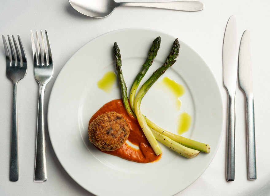 Plate of arancini, asparagus and a red sauce.