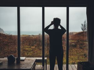 Person looking out of studio to landscape of grassland and sea