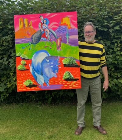 Man stood on grass against a hedge, wearing glasses and a stripey black and yellow top, holding up a large colourful canvas painting.