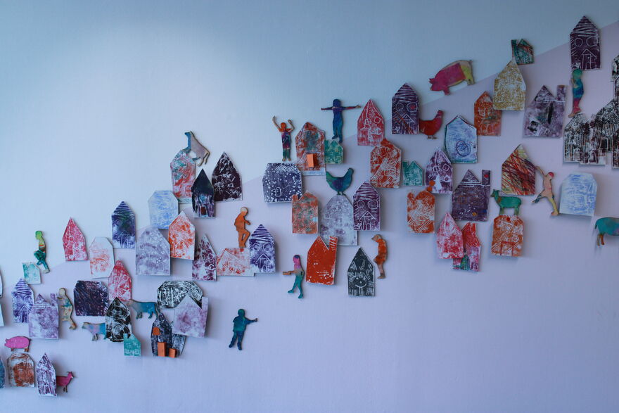 cut out card houses hung on a white wall.