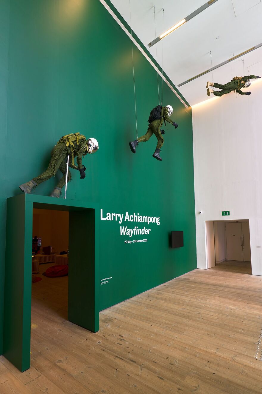 Title of exhibition and three mannequin figures in three stages of flight
