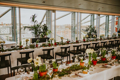Long tables in white tablecloth covered with green and white views with a large window in the background displaying views of the river Tyne.