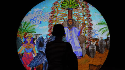 Silhouette of a person stood in front of a lit circular image. 