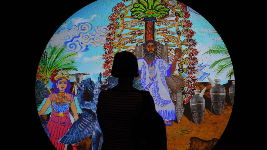 Silhouette of a person stood in front of a lit circular image. 