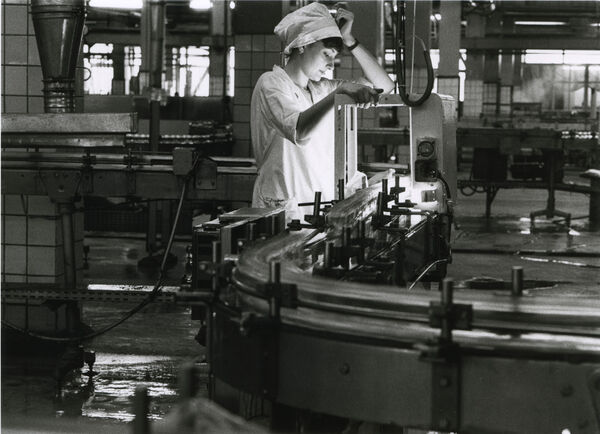 Black and white photo of a woman working in a factory.