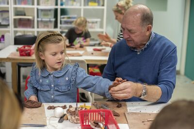 Adult and child making clay sculpture together