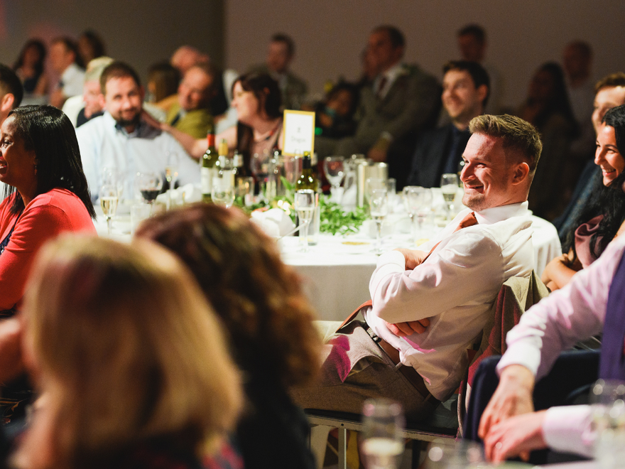 People sat around tables smiling and dressed smart in suits and dresses.