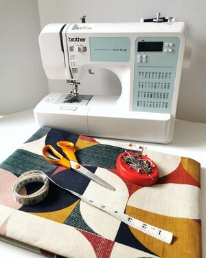Sewing machine, pins, fabric, scissors and tape measure