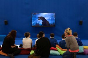 Children and adults watching a film in a blue room