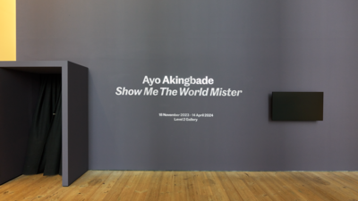 A purple wall with exhibition title in white letters