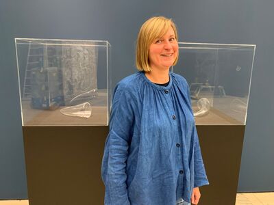 Artist with artworks, two brown plinths with glass objects and clear covering