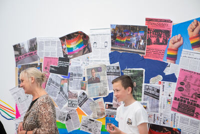Newspaper cutouts on the wall with people in the foreground