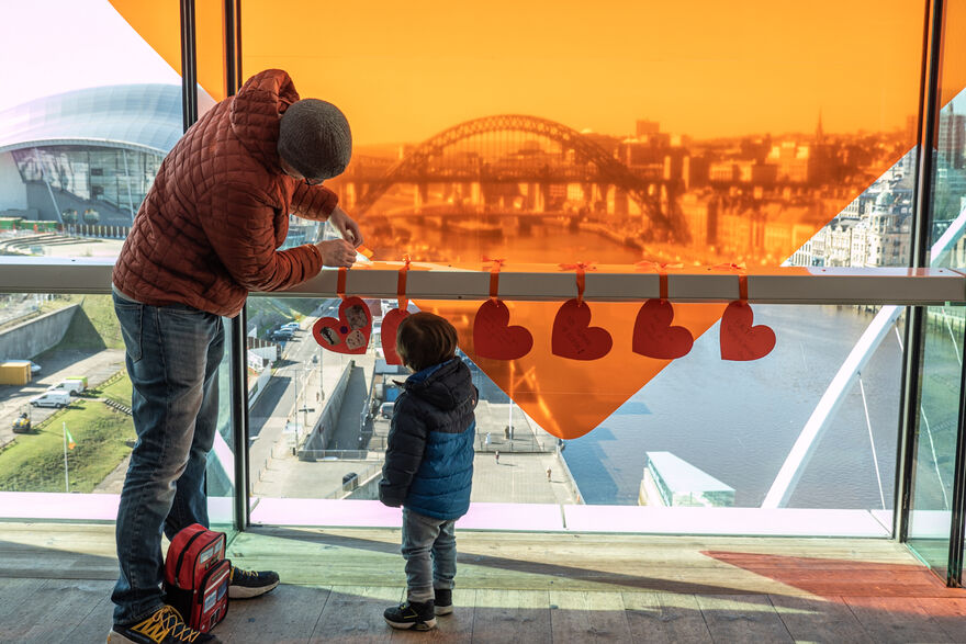 Adult and child hanging up paper hearts