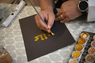 Hand with brush, painting with gold paint