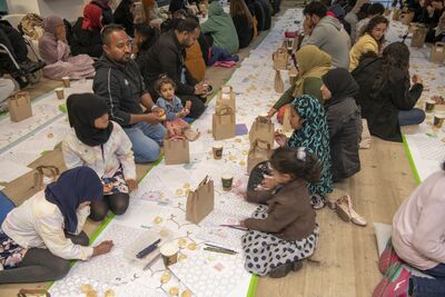 Rows of people sat on the floor, eating and drawing