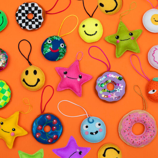 A collection of colourful felt christmas decorations against an orange background