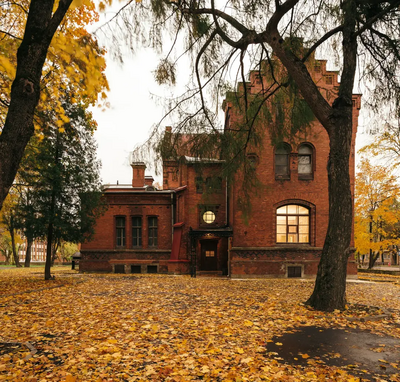 Old brick building surrounded by trees and golden fallen leaves.