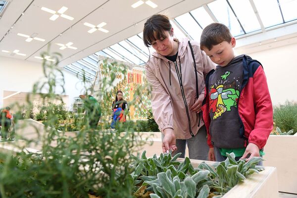 An adult and child touching the soft leaves of plants in the exhibition