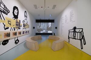 Film projection with curved benches in front and child-like drawings on the wall. 