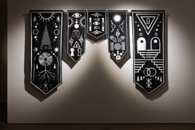 5 black banner crests hanging down with white images on them