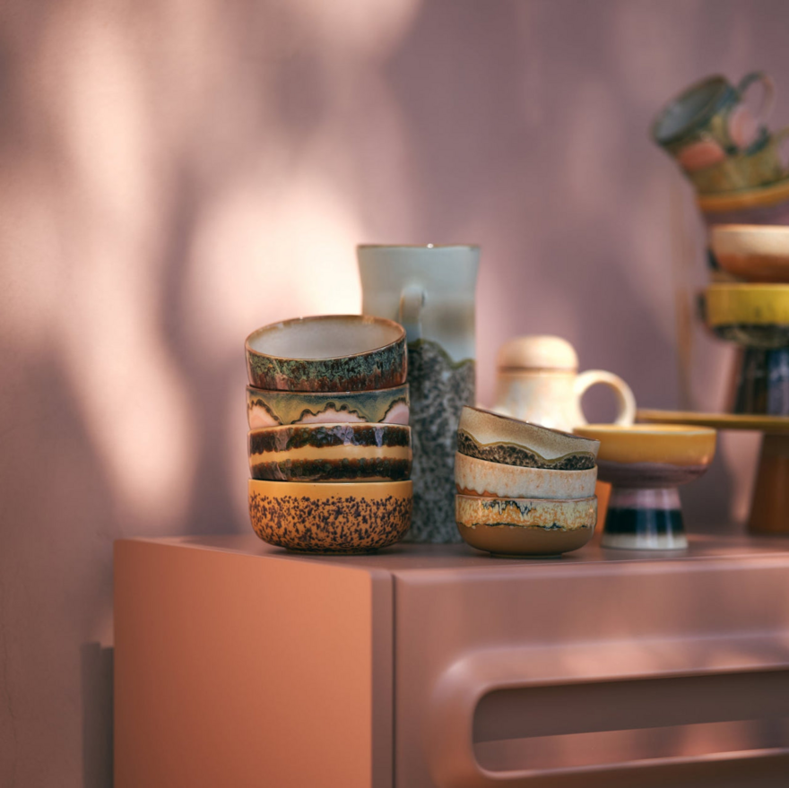 Stack of colourful 1970s style bowls, jugs and mugs.