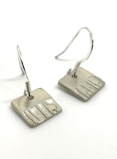 Square silver earrings with shapes stamped into them.