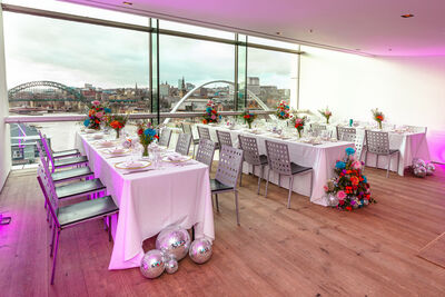 Long tables covered in colourful flowers and silver balls with a view over the river Tyne