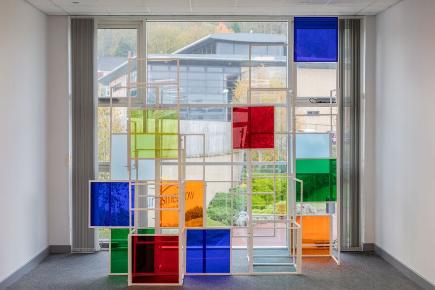 Sculpture with coloured panels, stood in front of window