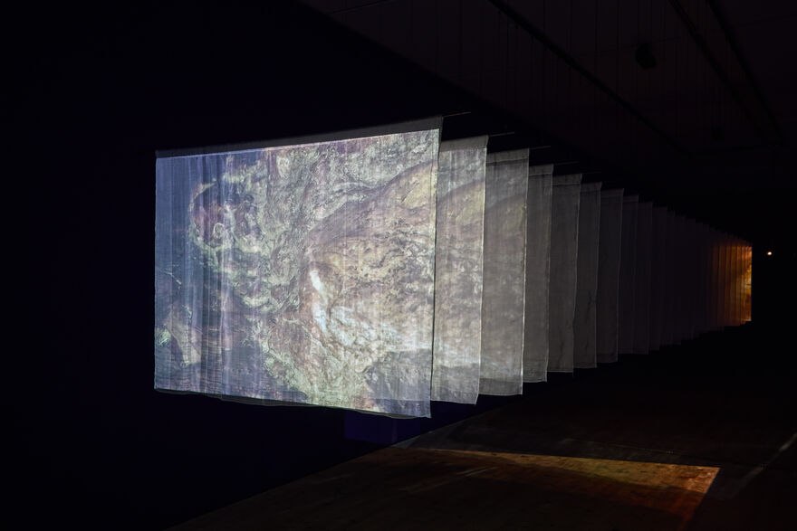 A series of hung silk sheets with a projection of a film onto the sheets.