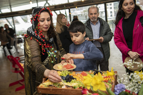 Woman and young boy stood together and helping themselves to a tray full of colourful fruit.