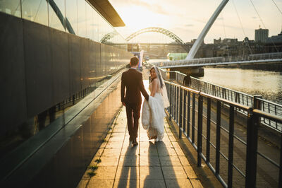 a bridge and groom walking into the sunset next to the River Tyne.